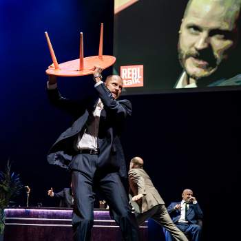 Man i kostym håller i bord falstaff